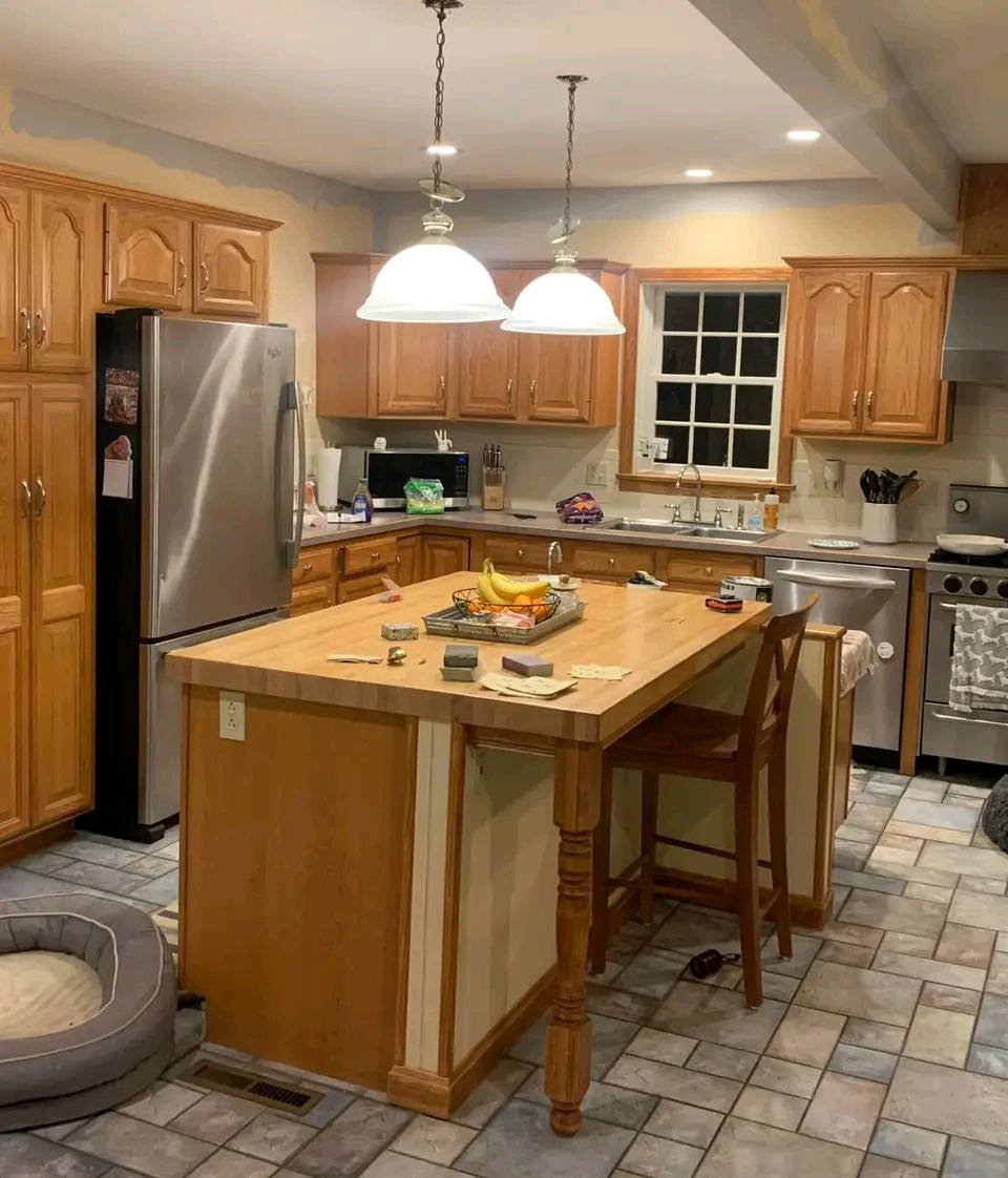 Outdated oak cabinets with wood butcher block island, cluttered counters, stainless appliances, and pendant lighting before kitchen remodel Salt Lake City