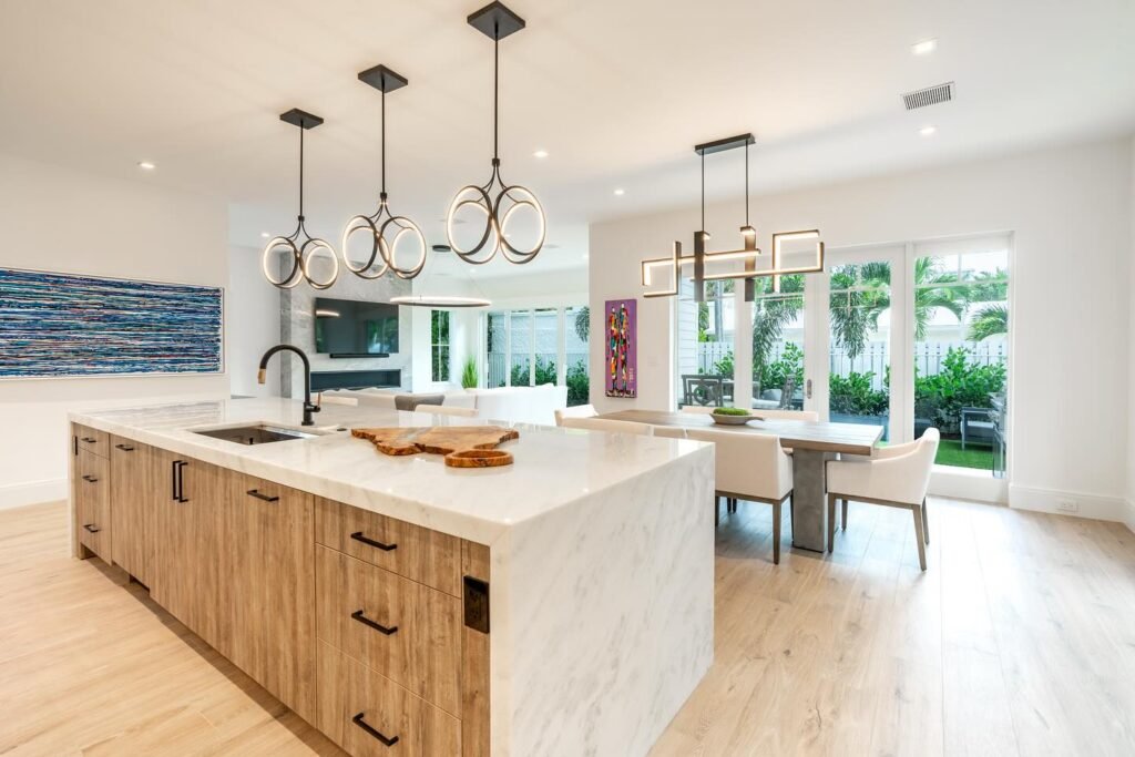 Modern open-concept kitchen with large marble waterfall island, wood lower cabinets, black fixtures, and contemporary pendant lighting in kitchen remodel Salt Lake City